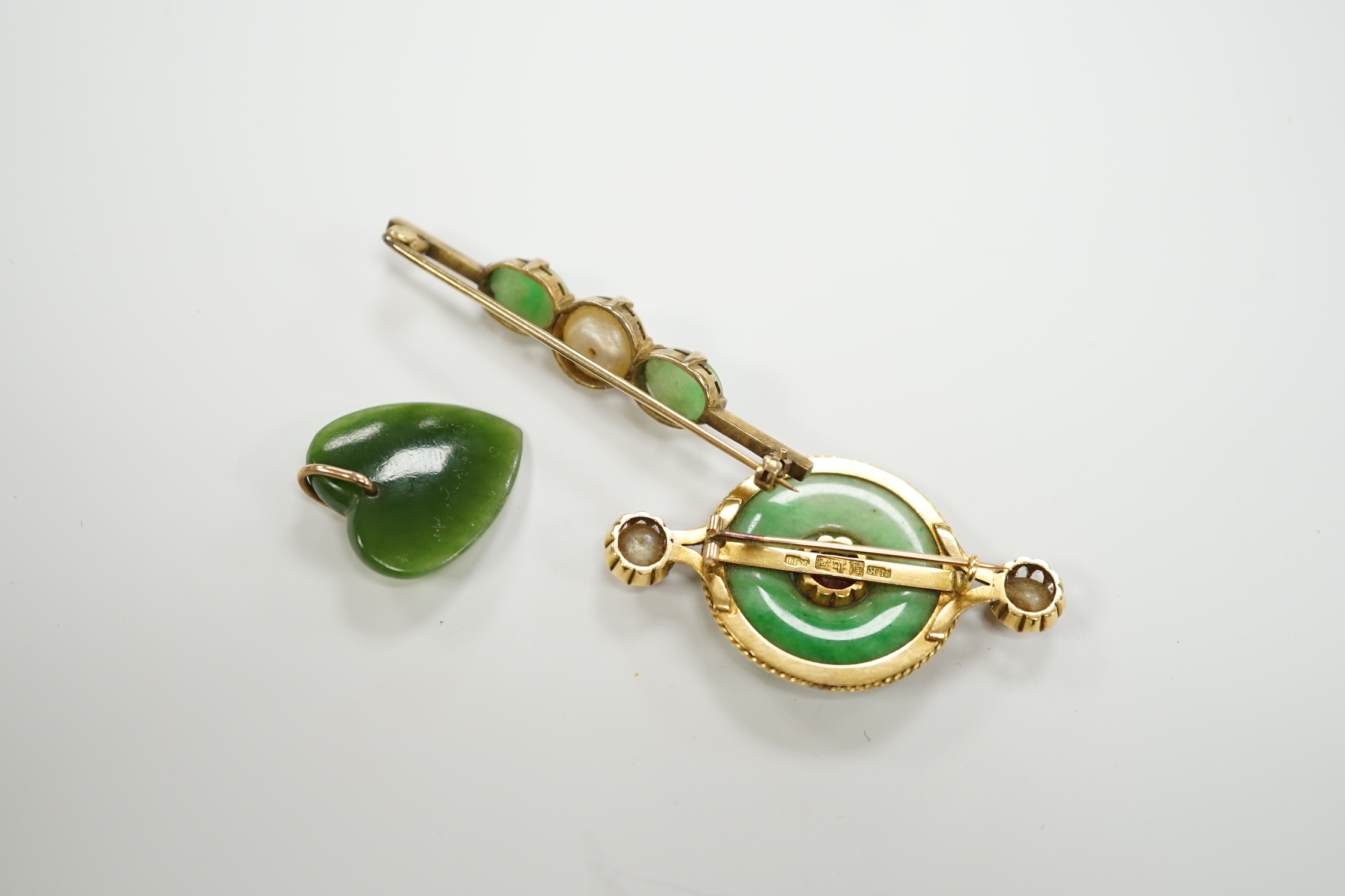 A Chinese 18k mounted, jade, cultured pearl and gem set disc brooch, 48mm, together with a yellow metal, jade and cultured pearl set bar brooch and a nephrite pendant.